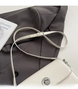 Detail of adjustable shoulder strap and silver twist lock on off-white minimalist bag