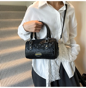 Detail of black faux python texture bag with gold hardware shown on a modern staircase