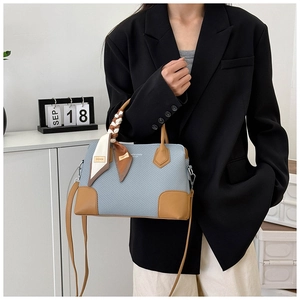 Détail du sac cabas tissé bleu avec anses en cuir marron et foulard en soie décoratif