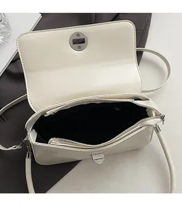 Detail of cream square crossbody bag showing secure zipper and turn-lock closure