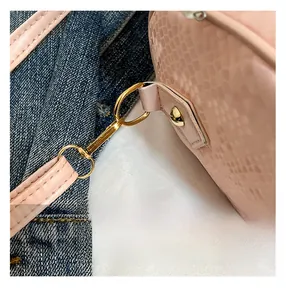 Close-up of pink embossed leather pillow bag with gold-tone hardware and fine stitching