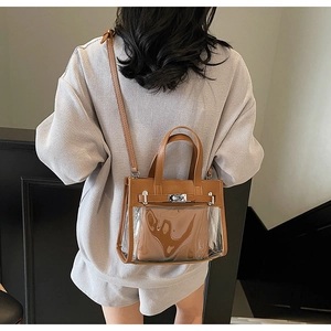 Dettaglio borsa Kelly in PVC trasparente con finiture in pelle marrone e chiusura