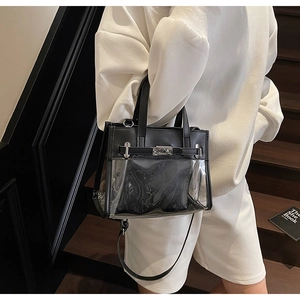 Dettaglio di una borsa Kelly in PVC nero con chiusura argento su una scala