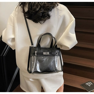 Dettaglio della borsa Kelly in PVC trasparente e pelle nera con chiusura a scatto