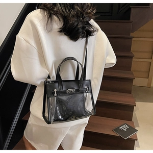 Dettaglio borsa Kelly in PVC nero trasparente con pochette su scale in legno