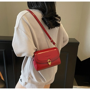 Vue détaillée d'un sac bandoulière en cuir rouge avec fermoir rotatif doré élégant