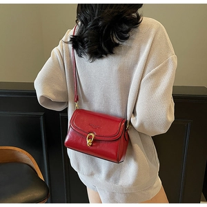 Vue latérale d'un sac bandoulière rouge avec boucle dorée porté par un mannequin