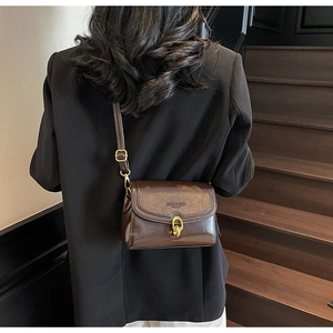 Détail d'un sac à bandoulière vintage marron foncé avec fermoir chaîne dorée