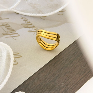 Detail of multi-layered spiral gold ring with wavy lines on elegant wood background