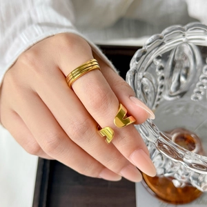 Detail of layered gold spiral rings on hand with elegant white sleeve and wooden tray