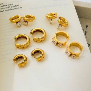 Collection of gold-plated star and zircon huggie earrings on vintage book page