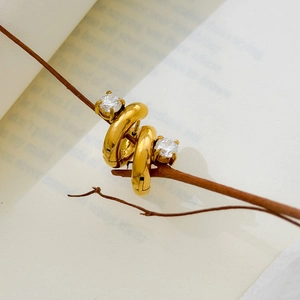 Close-up of gold plated hoop earrings with zircon stone on a rustic wooden branch