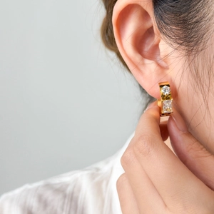 Macro detail of 18K gold plated huggie earring with round and baguette zircon stones