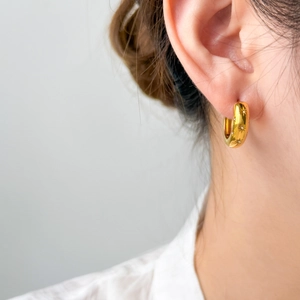Detailed close-up of gold starburst engraved hoop earrings with micro-inlaid zircons