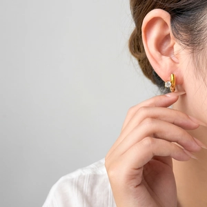 Gold-plated hoop earrings with sparkling zircon drop stone on an elegant model pose