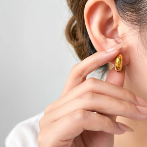 Gold-plated hoop earrings with star engravings and zircons shown on model ear