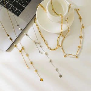 Elegant gold 18K plated oval chain necklaces with pearls shown in a stylish desk setting