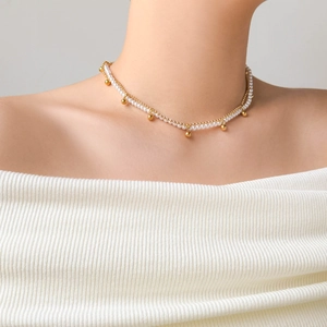 Detail of a layered choker featuring white pearls and golden beads on a double chain