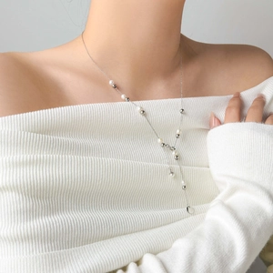 Elegant Y-shaped pearl necklace in silver steel finish worn on a white sweater