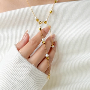 Detailed view of long Y-shaped pearl necklace with gold chain on model's white knit sweater