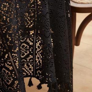 Vintage black crochet lace tablecloth with elegant floral cutouts and tassel fringe edges