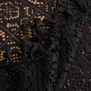 Detail of black crochet tablecloth featuring bohemian lace patterns and fringe tassels