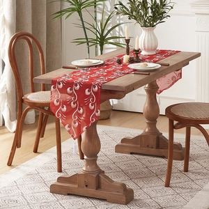 Detailed close-up of red Chinese table runner with white floral embroidery and tassels