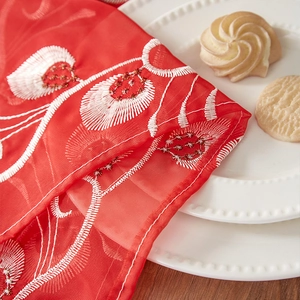 Close-up of white peacock feather embroidery on a red classical table runner