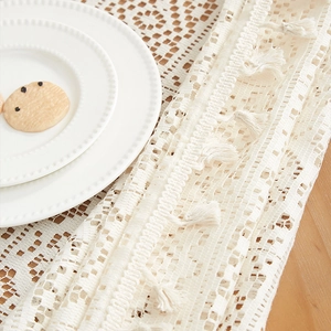 Detail of vintage crochet lace tablecloth with elegant tassels on a wooden table