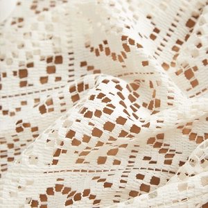 Macro view of white hollow crochet tablecloth with geometric lace patterns