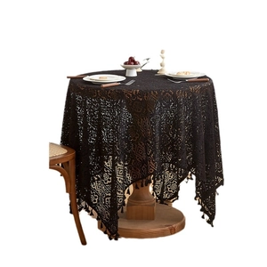 Elegant black crochet lace tablecloth with fringe edge on a vintage wooden round table