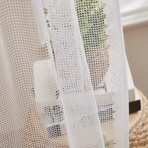 Détail du rideau en dentelle blanche montrant les bords au crochet et la texture