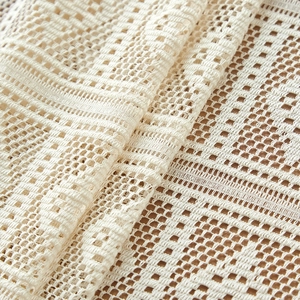 Macro shot of ivory hollow-out crochet fabric with vintage geometric pattern textures