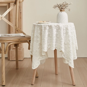 Macro view of white daisy lace tablecloth with 3D embossed pattern and wavy edges