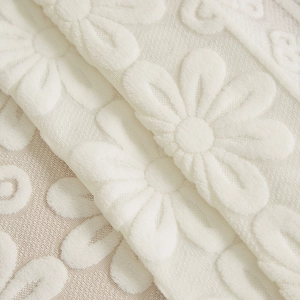 Close-up of white knitted lace tablecloth with 3D embossed daisy floral patterns