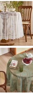 Detail of white and sage green lace round tablecloth with vintage floral embroidery