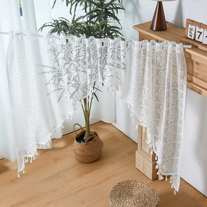 Detail of white crochet lace door curtain with floral patterns and fringe tassels