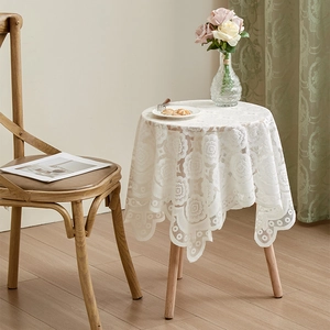Detail of white round lace tablecloth featuring elegant rose patterns and scalloped edges