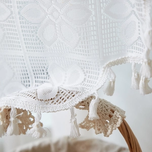 Detail of white French lace curtain with floral cutouts and decorative tassels