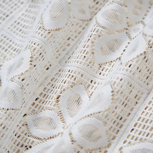 Macro detail of white French lace fabric with delicate geometric mesh and hollow patterns
