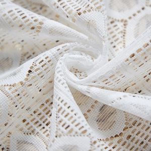 Macro shot of white hollow lace fabric with geometric bohemian crochet patterns