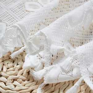 Close-up of white lace curtain fabric featuring delicate hollow patterns and tassels