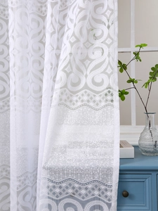Detailed close-up of white lace curtain showing intricate jacquard patterns and scalloped edges
