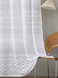 Detailed close-up of white lace curtain with intricate scrollwork on a wooden chair