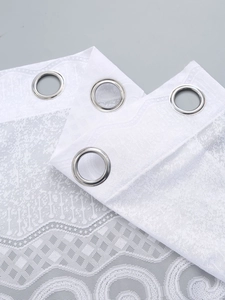 Detailed close-up of white lace curtain fabric showing intricate floral patterns and metal eyelets