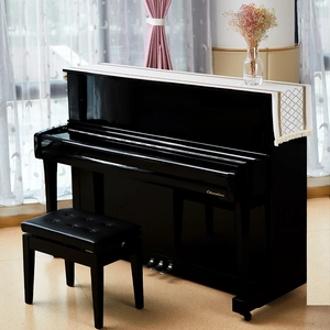Black upright piano featuring white diamond quilted dust cover with elegant gold tassels
