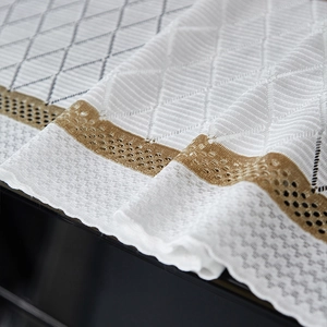 Close-up of geometric textured cotton linen piano cover with luxury golden lace edge