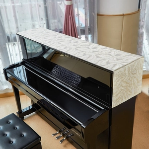 Detail van crème-witte linnen pianohoes met prachtig geborduurde bladpatronen