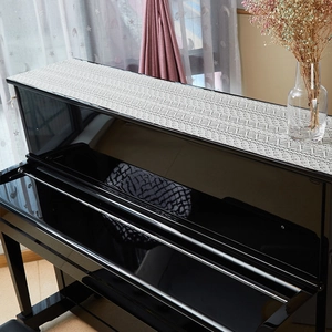 White lace piano top cover with geometric cutouts on a black upright piano