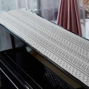 Elegant beige lace piano cover with geometric hollow patterns on a black piano surface
